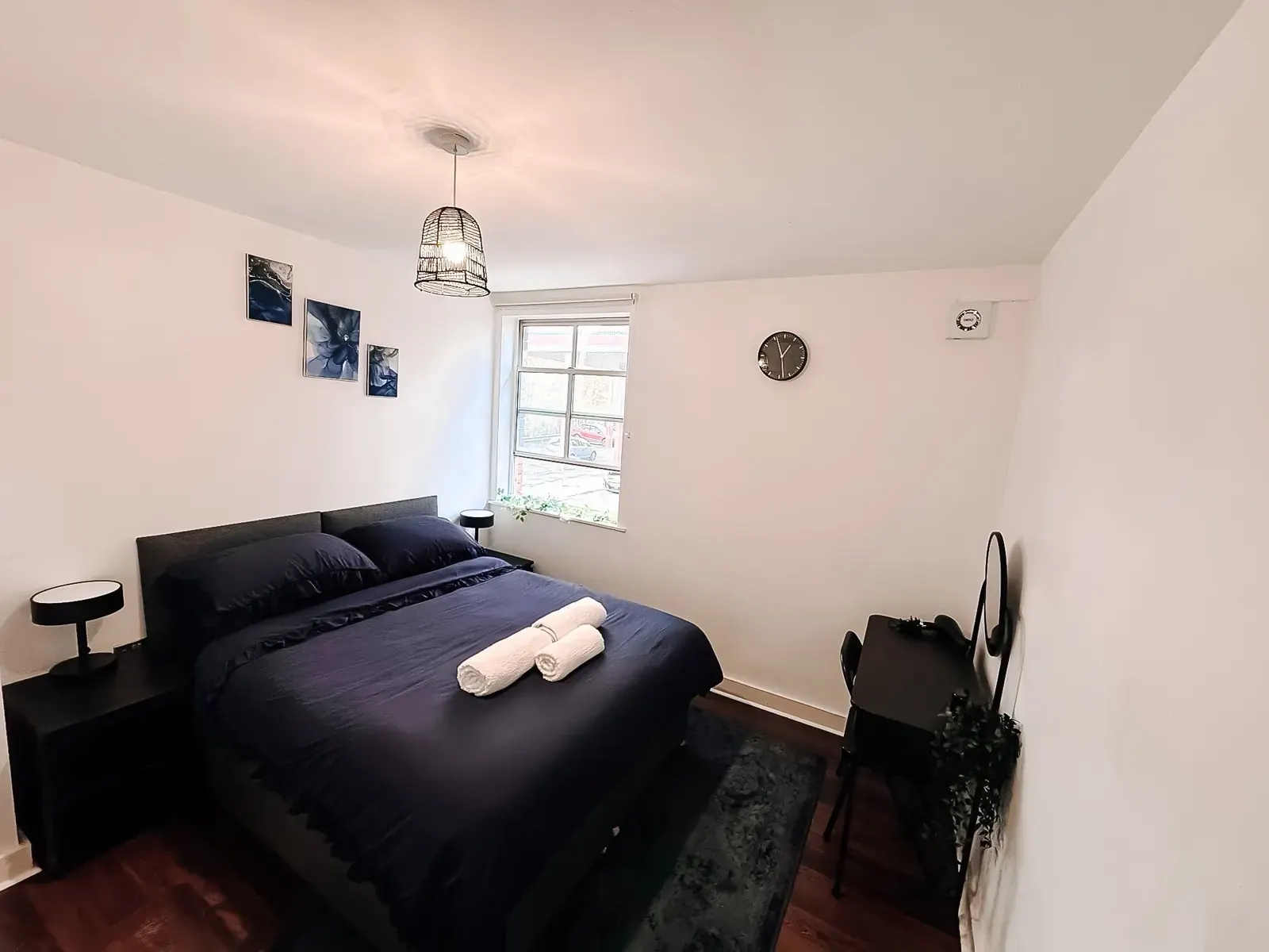 Bedroom with a navy double bed, towels and pendant light