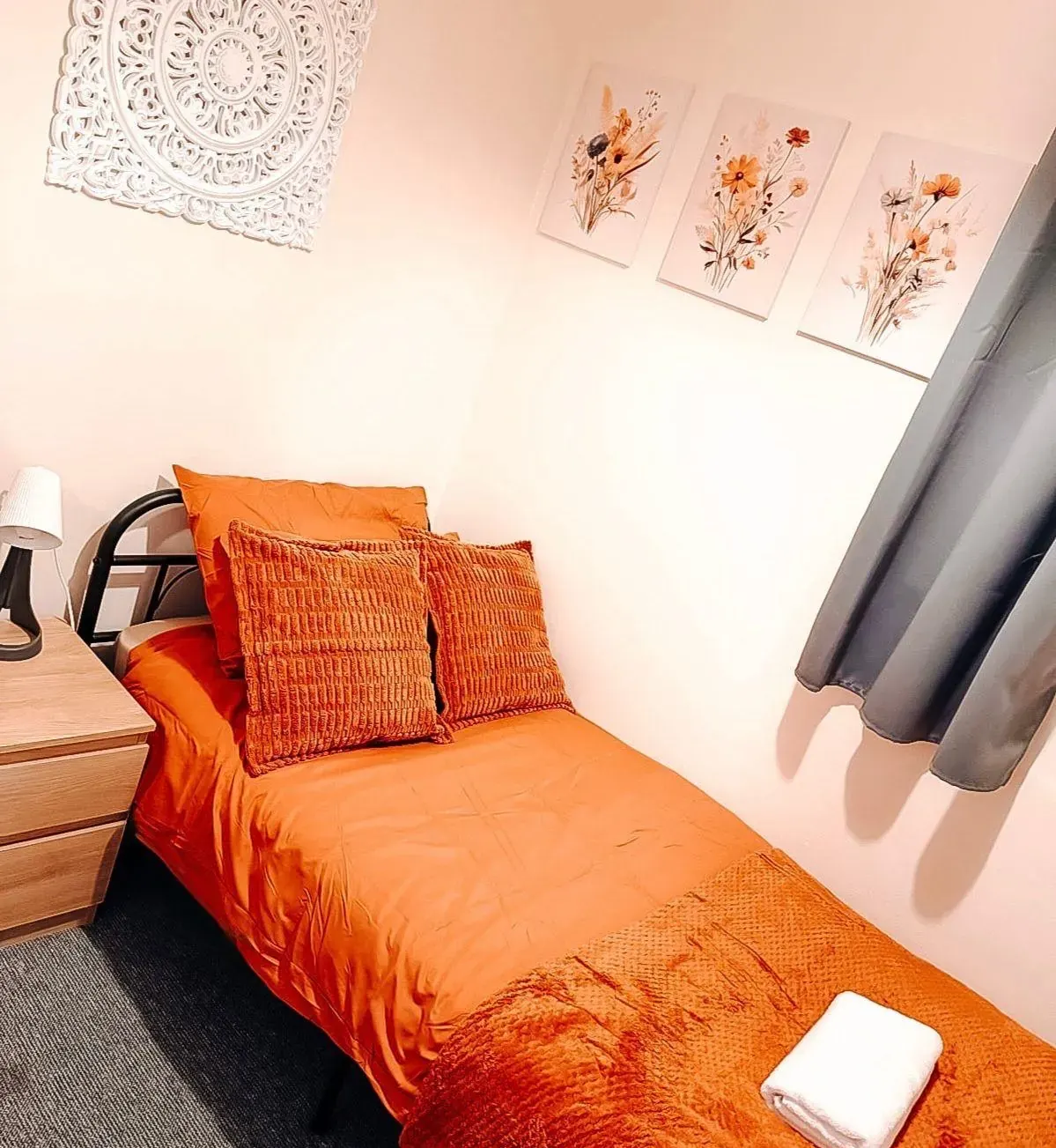 Bedroom with a single bed in orange linen and floral prints