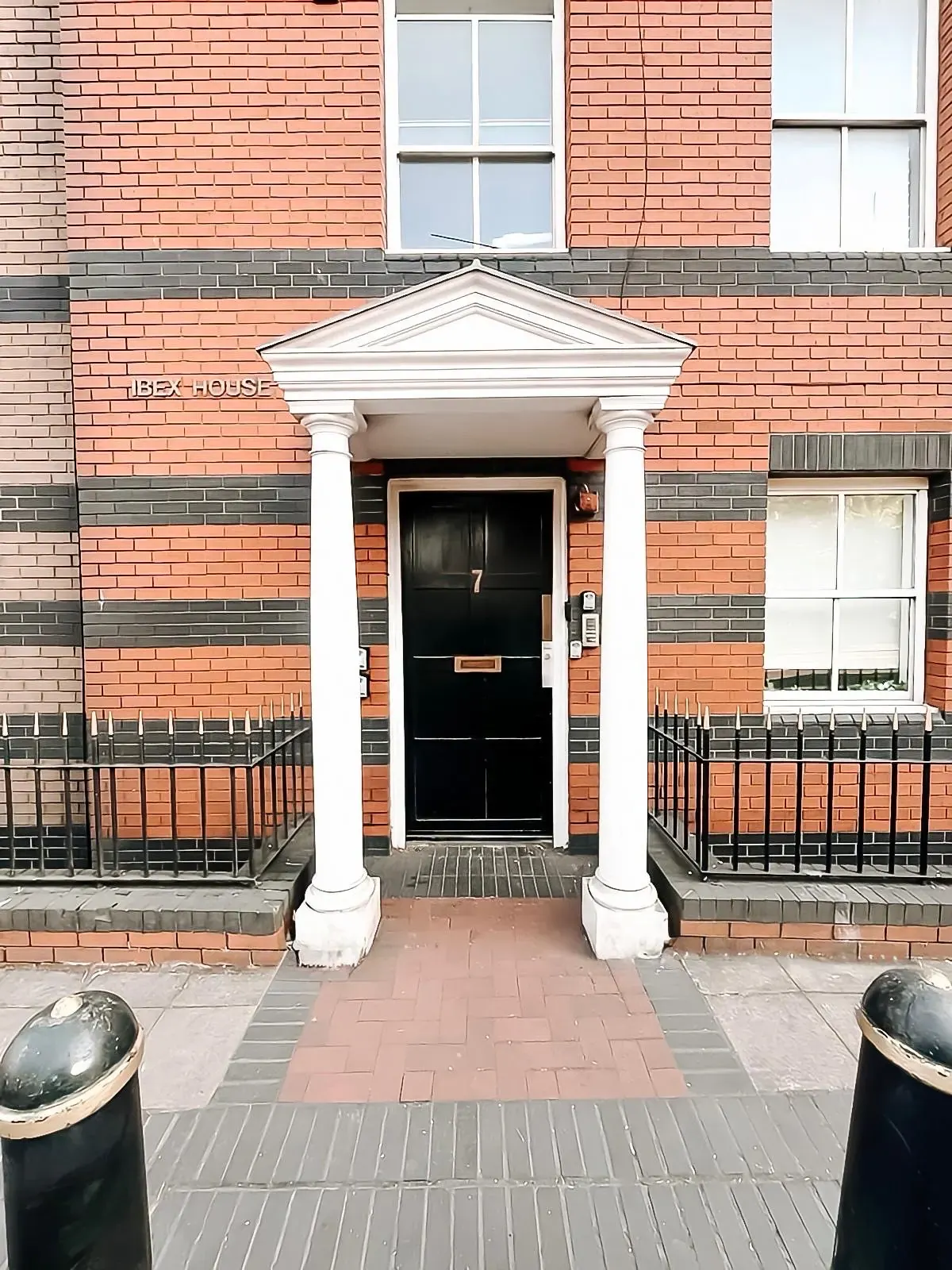 The entrance to Ibex House, Southampton: a black panelled door under a white portico in red and black brick