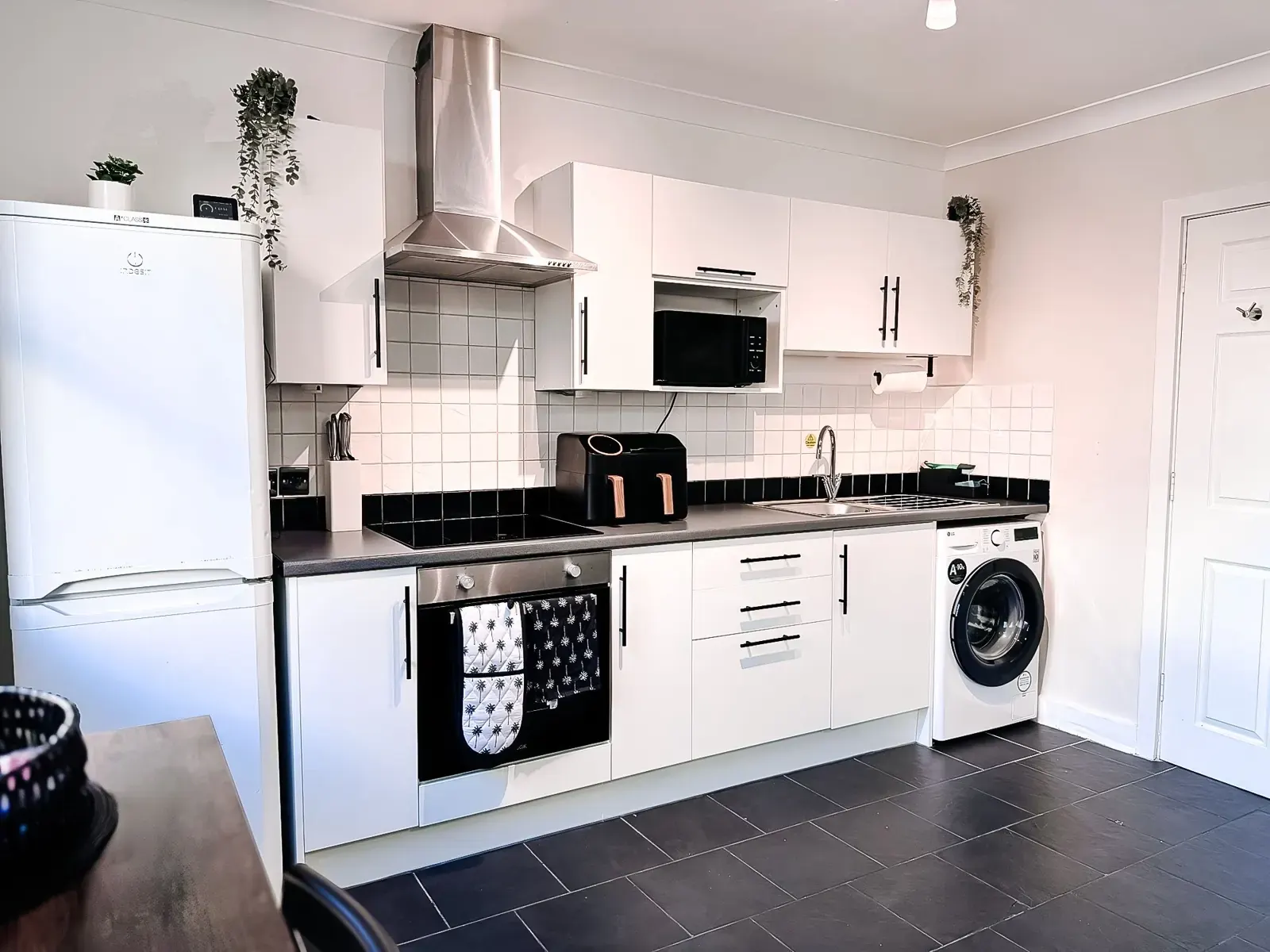 Fully equipped white kitchen with black handles and slate floor