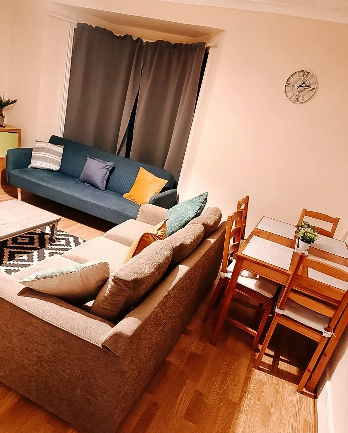 Living room with a taupe sofa, blue sofa and dining table beyond